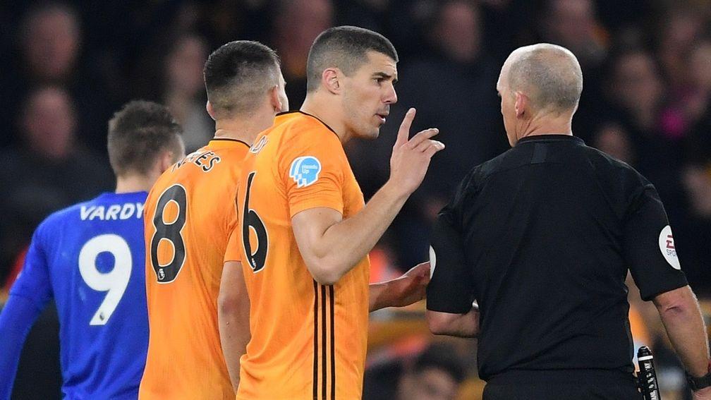Conor Coady argues with match referee Mike Dean during Wolves v Leicester