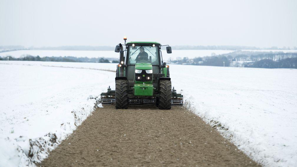 Making tracks: a tractor clears the gallop in Lambourn