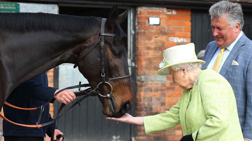 The Queen feeds carrots to Frodon as Paul Nicholls looks on