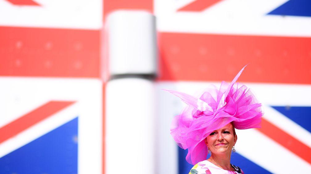 A racegoer stands in front of the Union Jack flag on the stand