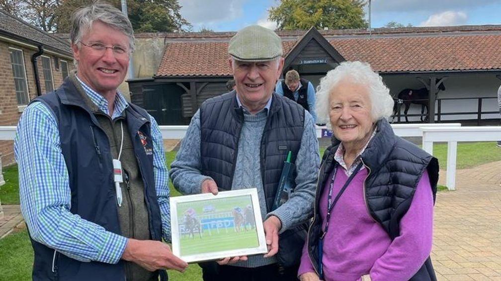 Oliver St Lawrence presents Geoffrey Howson with a framed photograph of his Classic-winning buy Phoenix Of Spain, who was co-owned by Ann Plummer (right)