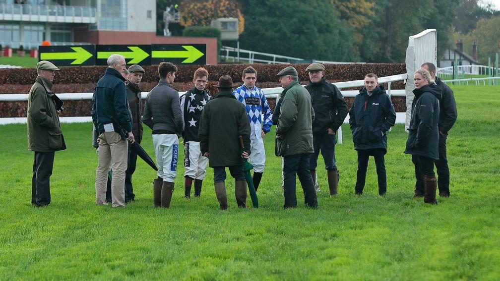 A group of jockeys, trainers and officials inspect the track at Sandown