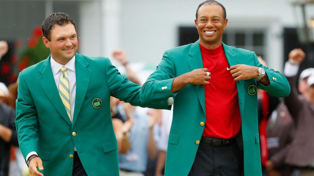 Tiger Woods gets a pat from 2018 champion Patrick Reed as he puts on his fifth Green Jacket