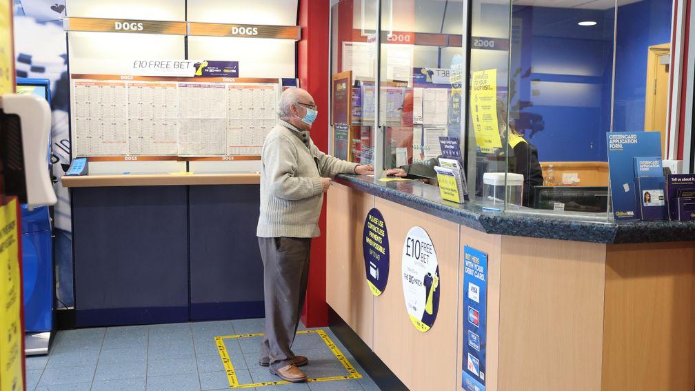 A customer places a bet socially distanced after betting shops opened on April 12