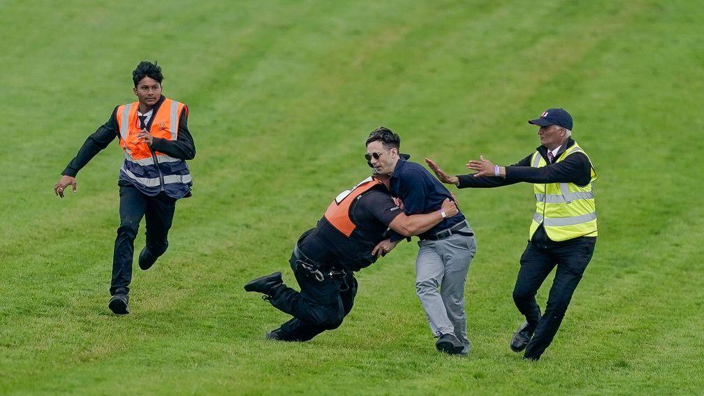 A protester runs on to the course and is tackled to the ground on Derby day at Epsom