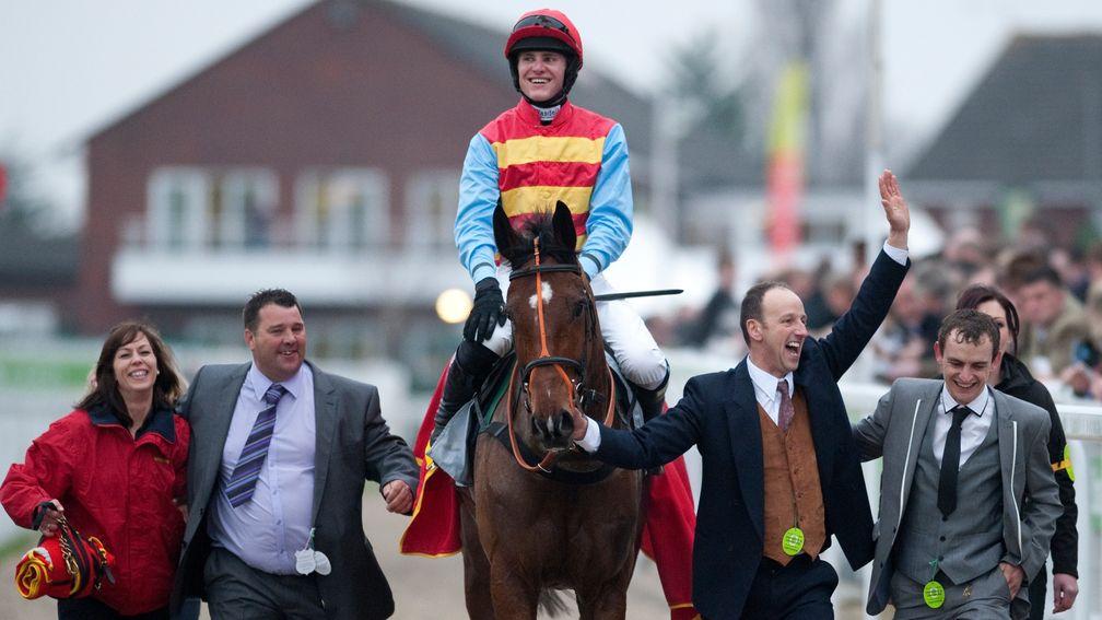 The smile says it all... Nick Scholfield and Hunt Ball are escorted back to the Cheltenham winners' enclosure by owner Anthony Knott (waving) and trainer Kieran Burke (right of picture)
