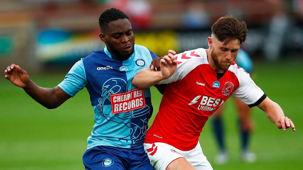 Wes Burns of Fleetwood Town is challenged by Adebayo Akinfenwa of Wycombe Wanderers during the first leg