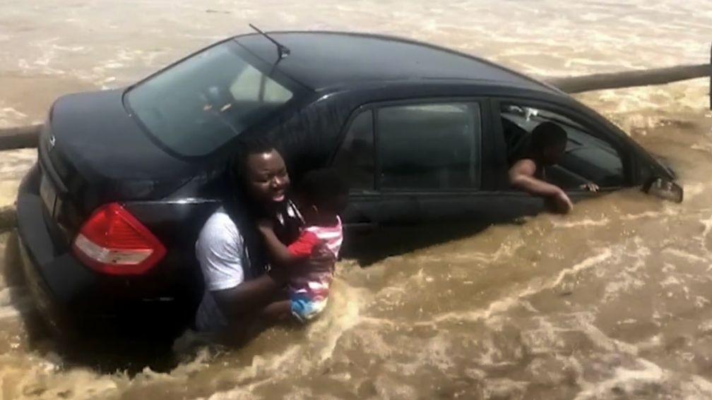 The father holds one of his four children as his car is caught in the rising floodwater in Pennsylvania