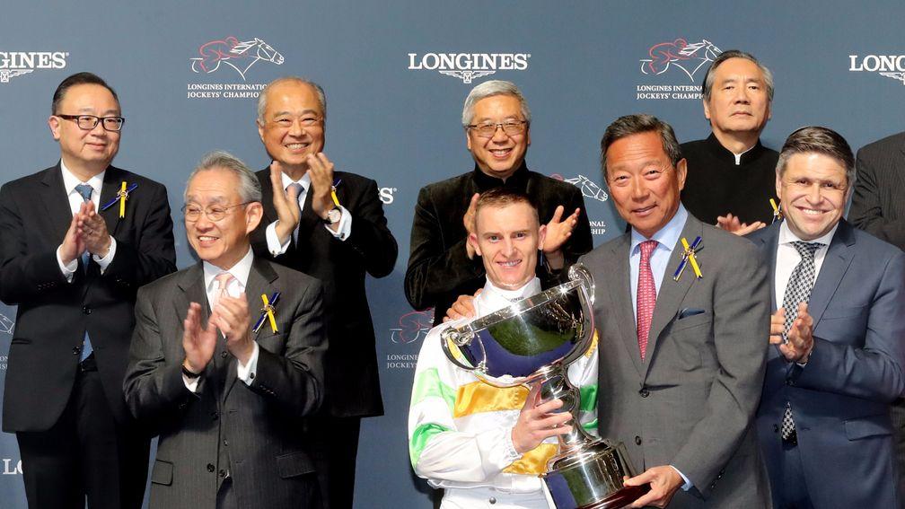 Chairman of the Hong Kong Jockey Club Dr Simon Ip presents Zac Purton with his trophy