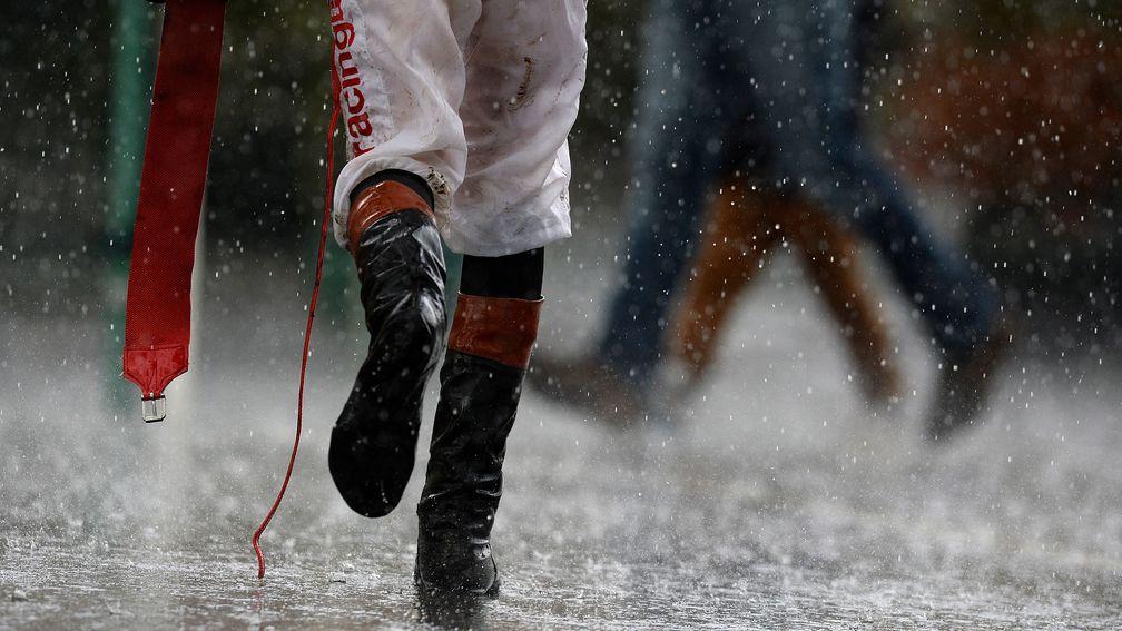 A jockey runs through the rain after The Betfred Nursery Handicap Stakes at Doncaster