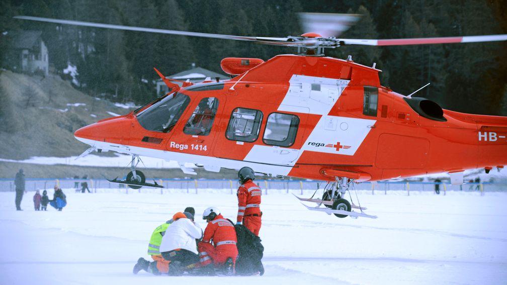 Paramedics attend a stricken George Baker on the frozen lake at St Moritz while a helicopter stands by to airlift him to hospital