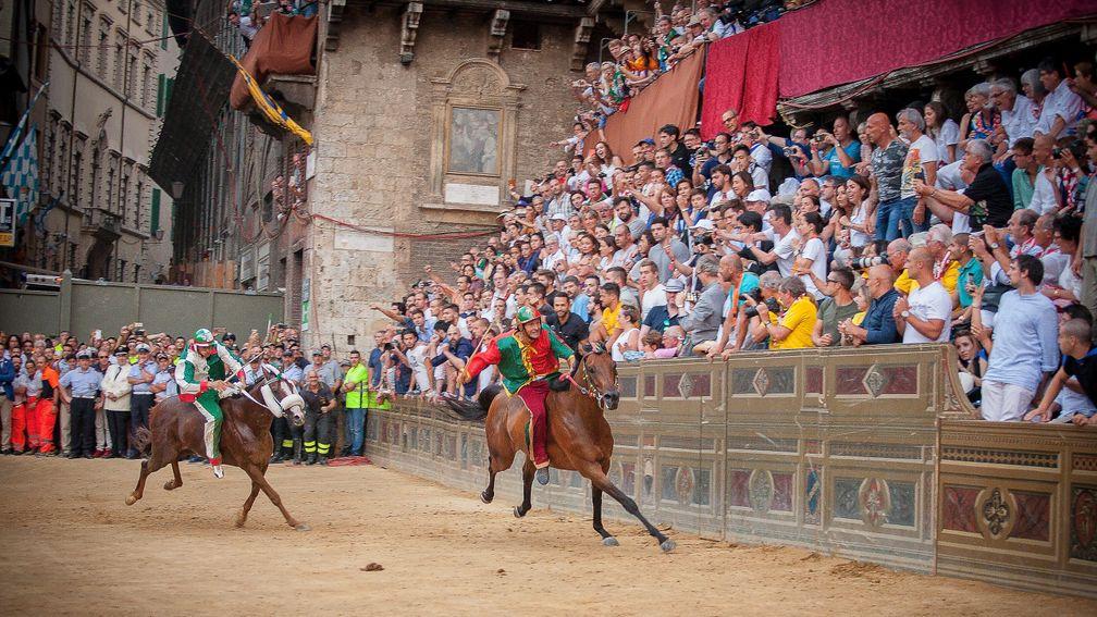 Mediaeval memories: colourful riders in front of a frantic 'Il Palio' crowd in Siena's Piazza del Campo