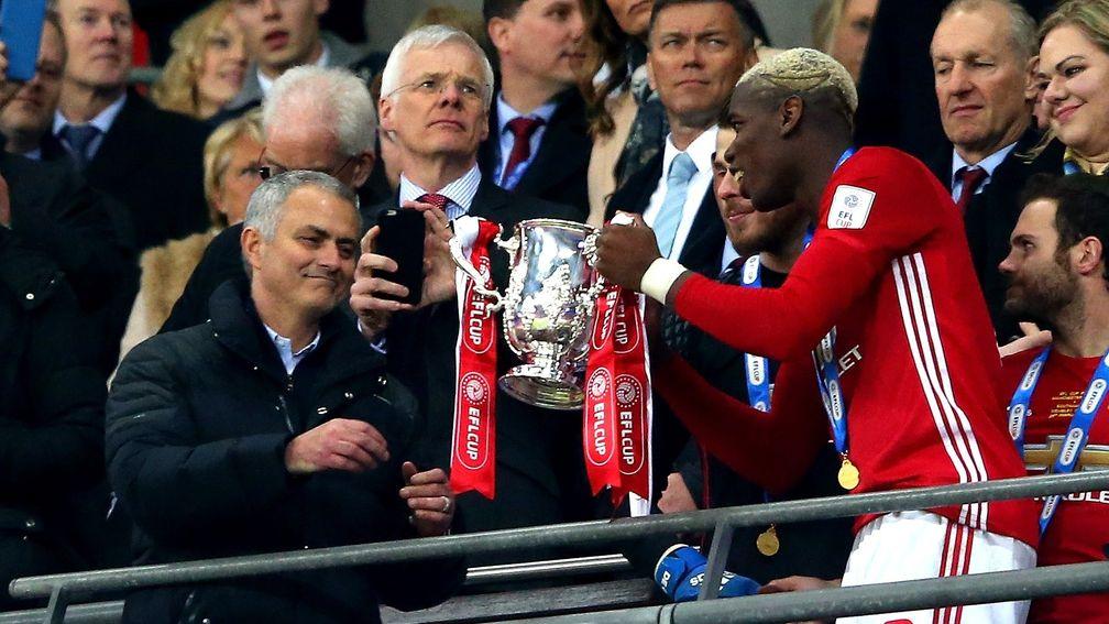 Paul Pogba passes the 2017 EFL Cup trophy to Jose Mourinho